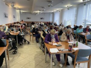Prebivalci doma starejših občanov sedijo za mizami in igrajo tombolo